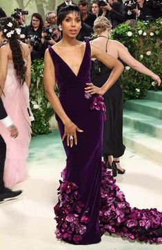 a woman in a purple gown standing next to other people