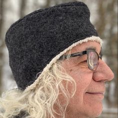 an old man wearing glasses and a black hat is looking off into the distance with trees in the background