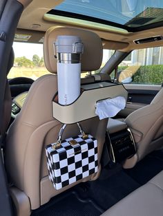 the back seat of a car with a checkered purse and cup holder on it