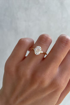 a woman's hand with a diamond ring on her left hand, against a white background