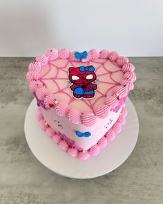 a heart shaped cake decorated with pink icing and a spiderman face on top