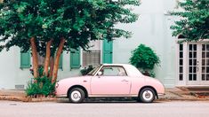 a pink car parked in front of a tree