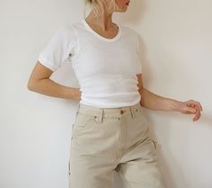 A must-have basic. Deadstock vintage cotton ribbed tee from 70s-early 80s. Ribbed 100% cotton. Soft & comfy. Knit trim around sleeves & neckline. Mint condition. We currently have a small group of these available, each one is unique.  Measurements are taken with the garment laying flat. No tag size, fits like S-M  Shoulder to shoulder = 14 in / 36 cm Armpit to armpit = 16.5 in / 42 cm Sleeve length = 9 in / 23 cm Total length= 28.5 in / 72 cm Model is 5'6", 26" waist, 36" hip and wears a modern Knit T Shirt, Vintage Overalls, Ribbed Tee, Denim Dungarees, Green Quilt, Scoop Neck Tee, Knit Short, Knitted Tshirt, Knit Shorts