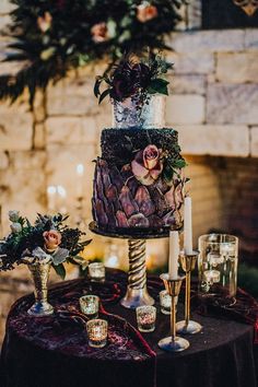 a wedding cake sitting on top of a table next to candles and vases filled with flowers