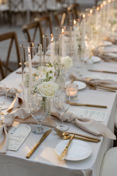 the table is set with white flowers, candles and napkins for an elegant dinner