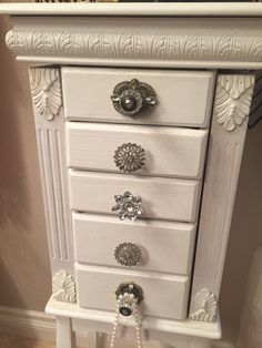 a white dresser with drawers and knobs on it