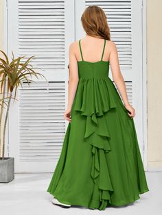 a woman in a long green dress is standing near a door and looking down at the floor