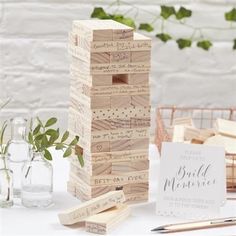 a wooden block tower sitting on top of a table next to some pens and pencils