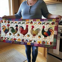 a woman holding up a quilt with roosters on it in front of an oven