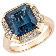 a large blue stone surrounded by diamonds in a gold ring with two rows of pave stones