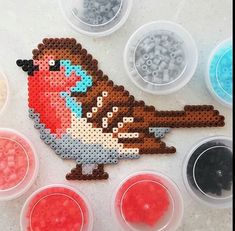 beaded bird sitting on top of plastic containers filled with beads and other crafting supplies