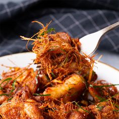 a white plate topped with meat covered in sauce and sprinkled with green onions