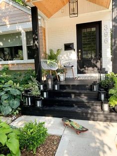 a contrasting modern porch with a black floor and ladder, white chairs, a side table, black candle lanterns and potted greenery Sunroom Remodel, Brick Porch, White Exterior Houses, Exterior Makeover, White Brick