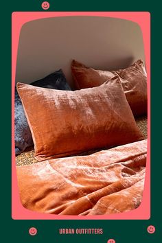 an orange bed with two pillows on it and a pink frame over the top that says urban outfitters