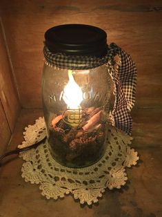 a mason jar filled with dirt and a lit candle on top of a doily