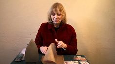 a woman sitting at a table with an object in front of her and pointing to it