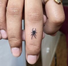 a person with a small spider tattoo on their finger