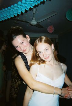 two young women are dancing at a party