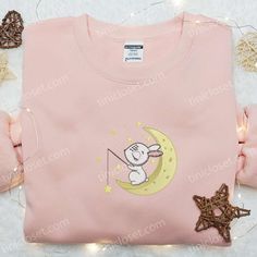 a pink shirt with an image of a mouse on the moon and stars around it