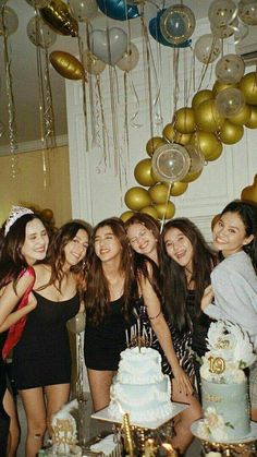 a group of young women standing next to each other in front of a birthday cake