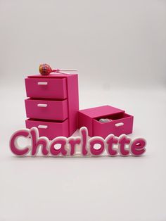 the word charlotte spelled out in pink and white with drawers on each side for storage