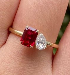 a woman's hand holding a red and white ring with two diamonds on it