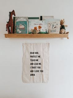 a shelf with books and stuffed animals on top of it next to a white wall