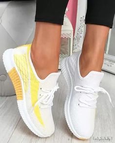 a woman's feet in white and yellow sneakers