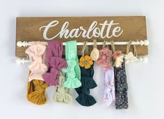 a wooden sign that says charlotte with many different bows hanging from it's hooks