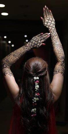 a woman with henna tattoos on her arms and hands is shown from the back