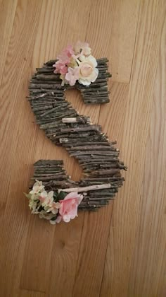 the letter s made out of sticks and flowers on top of it, sitting on a wooden floor