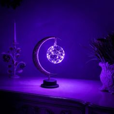 a purple light shines on a table next to an owl figurine and a lamp