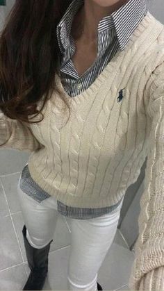 a woman is taking a selfie in the mirror wearing white pants and a sweater