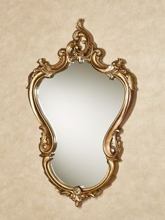 an ornate gold framed mirror on the wall in front of a beige wallpapered background