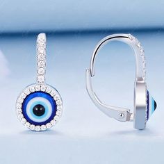 These Turkish evil eye dangle drop earrings are crafted from 925 sterling silver and feature cubic zirconia stones set in an ornate evil eye design. The blue enamel color adds to the protective powers of these stylish earrings. Offering protection from envy with both fashion and function, they are perfect for everyday wear or for special occasions. The latch back closure ensures they stay comfortably in place all "evil eye" long, while the sterling silver offers lasting durability. Slip these ev Sterling Silver Dangle Evil Eye Jewelry, Sterling Silver Evil Eye Teardrop Jewelry, Sterling Silver Teardrop Evil Eye Jewelry, Silver Round Evil Eye Earrings, Sterling Silver Evil Eye Dangle Earrings, Elegant Evil Eye Drop Earrings, Blue Sterling Silver Evil Eye Earrings, Silver Dangle Jewelry With Diamond Eyes, Evil Eye Cubic Zirconia Jewelry