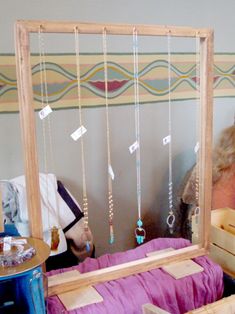 a woman sitting in front of a mirror with necklaces hanging from it