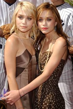 two young women standing next to each other in front of baseball players at a game