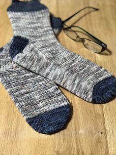 a pair of eyeglasses sitting on top of a wooden floor next to a sock