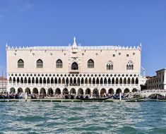 a large building sitting on top of a body of water next to a pier with gondolas