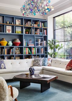 a living room filled with lots of furniture and bookshelves next to a window