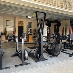 an indoor gym with machines and other equipment in the garage, along with american flag hanging on the wall