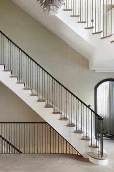 a white staircase with black railings and a chandelier