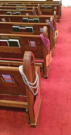 rows of wooden church pews with rope on each side and red carpeted floor