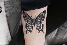 a black and white butterfly tattoo on the leg