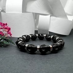 Get ready to rock and roll with this Black Skull Beaded Bracelet featuring Metallic Silver Steel Tone Disk/Round Beads. The perfect accessory for cool guys who love to add an edge to their style. Whether it's for a casual autumn look, a spooky Halloween vibe, or just everyday fashion, this adjustable elastic wristband is a must-have! Embrace the Mexican Dia de Muertos spirit with this Calacamania™ jewelry piece. • GET IT FAST!Get it fast! Ready to ship on 1 to 3 business days. • ORDER NOW!Limited Quantities / Limited Edition. • FREE GIFT BOX INCLUDED!Get a Free Craft Gift Box with any order* Thank you for stopping by!_______________________ *Colors/Designs might slightly vary from actual. Black Edgy Bracelets As Gift, Adjustable Punk Beaded Bracelets As Gift, Edgy Black Band Bracelet As Gift, Edgy Black Band Bracelet For Gift, Edgy Bracelet With Black Band As Gift, Black Letter Beads Bracelets For Parties, Black Letter Beads Bracelet For Party, Black Bracelets With Letter Beads For Party, Black Party Bracelet With Letter Beads