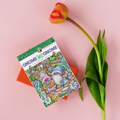 an orange flower next to a book on a pink surface with the title gnome's gnomeme