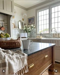 a kitchen with marble counter tops and wooden cabinets, along with a basket of fruit on the counter