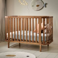 a wooden crib in a white room with a fish wall hanging above the crib