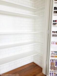 an empty pantry with white shelving and wood flooring in the corner between two walls