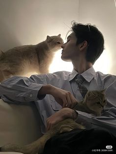 a man sitting on top of a couch next to a cat and looking at him